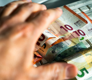 Hand greift nach Geldscheinen